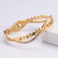 Vista macro di un bracciale traforato dorato con strass incastonati su cubo bianco - Oro