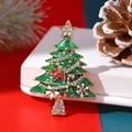 Spilla ad albero di Natale con cristalli verdi e base dorata su sfondo festivo in legno - Verde