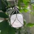 Detailed macro of a raw crystal stone encased in a silver mesh cage necklace pendant - White Crystal
