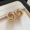 Macro shot of matte gold triple-layered twisted knot stud earrings on beige velvet - Silver Needle - Gold Frosted Interlocking Rings