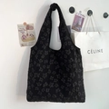 Minimalist black tote bag with 3D floral lace texture shown on a minimalist wall - Black Texture Small Flower