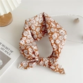 Orange and white floral cotton silk scarf styled with a knot on a white desk - Caramel Floral