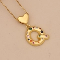 Close-up of golden heart pendant with colorful zircon letter Q on beige paper - Letter Q / Gold