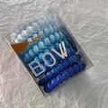 Detail of blue gradient spiral hair ties in a transparent box on white textured background - Blue
