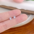 Close-up of mini silver stud earrings with clear zircon held to show small size - Vertical Prong No.4 / White