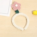 Detail of pink plush tulip headband with green leaves on a natural wood background - Pink Flower