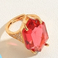 Macro detail of gold flower ring featuring a large red gemstone and zircon accents - Red Hexagon
