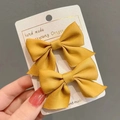 Detail of yellow fabric bow hair clips for girls set on a white display card - 2-Piece Set / Turmeric
