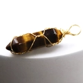 Handmade wire-wrapped tiger eye stone hexagonal prism pendant on a grey pedestal - Tiger's Eye