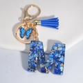 Royal blue resin letter M keychain with gold foil, blue tassel and butterfly charm - Letter M