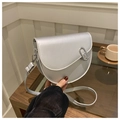 Detail of silver saddle bag with metal clasp and adjustable strap on a wooden table - Silver