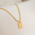Macro shot of gold-plated square pendant with letter E on a box chain over silk - Letter E