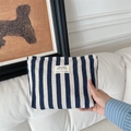 Detailed texture of blue striped cotton linen makeup bag held by hand on white background - Blue