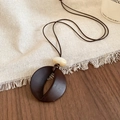 Detail of vintage resin round pendant on brown wax cord necklace over rustic wooden surface - Necklace-Coffee-Hollow Round