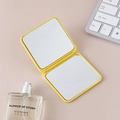 Petit miroir de poche carré pliable jaune vif sur un bureau rose élégant - Jaune