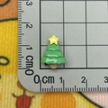 Macro shot of a mini green resin Christmas tree charm measured on a metric scale grid - Mini Christmas Tree