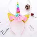 Detail eines Einhorn-Haarreifens mit Regenbogenhorn, goldenen Ohren und rosa Stoffblumen - Regenbogen-Einhorn