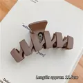 Matte brown 11.5cm large hair claw clip for thick hair shown on a decorative book - Matte N-Shape Dark Brown-11.5cm