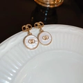 Detailed macro of gold flower heart earrings with white inlay and interlocking CD motif - Gold Circles