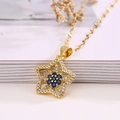 Collana con ciondolo a stella dorata con zirconi blu e trasparenti su sfondo di libri - Oro con zircone blu
