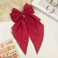 Detail of a large dark red silk bow hair clip with long ribbons on lace background - Burgundy