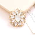 Elegant gold flower brooch with oval crystal and marquise rhinestones on a card - White