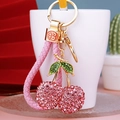 Pink rhinestone cherry keychain with golden ring and braided rope on a bright background - Pink Cherry with Pink Rope