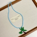 Close-up of handmade beaded necklace with a tropical green palm tree pendant detail - Style I Blue Beaded Coconut Tree