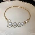 Elegante collar gargantilla dorado con perlas blancas sobre una bandeja de cerámica - Gargantilla de Perlas de Metal Dorado / Dorado