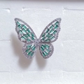 Close-up of a silver butterfly ring with green crystals in a white gift box - Green + Silver
