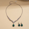 Detalle de conjunto de joyas de lujo con gota de esmeralda, cadena de plata y pedrería - Verde