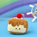 Close-up of a cute plush dessert pendant with a sweet smiley face and red pom-pom top - Triangle Cake