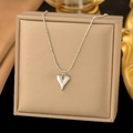 Detailed macro view of silver polished irregular heart pendant on fine bead chain - Heart / Steel