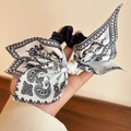 Close-up of black hair scrunchie with vintage black and white paisley bow accessory - Black and White Paisley Bow Hair Tie