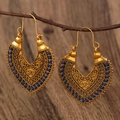Close-up of vintage hollowed-out earrings with blue woven thread on a natural branch - Antique Gold 0514