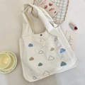 Détail de la broderie nuage et du logo sur un sac cabas en toile de coton crème - Style Nuage Bleu Clair (Sac Gilet)