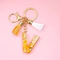 Detail of resin letter V keychain with orange stone chips, gold foil and colorful tassels - Letter V