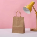 Eco-friendly brown kraft paper gift bag with matching paper handles in a studio setting - Natural / 21*15*8