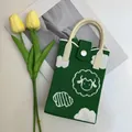 Detail of green knitted phone bag featuring cloud and lamb patterns with cream leather strap - Little Lamb Green