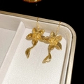 Détail des boucles d'oreilles fleur et feuille dorées dans un écrin à bijoux de luxe - Style Pendentif Fleur et Feuille Doré