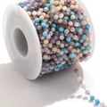 Colorful faceted glass bead chain with gold stainless steel links on a white spool - Gold-Blue Multi