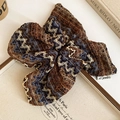 Détail macro d'un chouchou tricoté rétro avec motif zigzag et étiquette de marque tissée - Chouchou Géant en Tricot Vintage / Marron