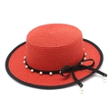 Dettaglio di cappello di paglia rosso con nastro nero, perle bianche e fiocco laterale - Rosso