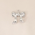 Macro shot of silver bow pendant with polished finish on a textured beige fabric - Simple Shiny Bow (PJ0134) / Silver
