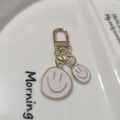 Close-up of pink enamel smiley face keychain charms on a white ceramic display tray - Small & Large Set Pink