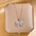 Élégant collier à pendentif nœud argenté avec strass brillants sur boîte à bijoux - Nœud (Argent) / Argent