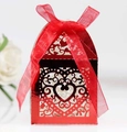 Close-up of red laser-cut wedding favor box with heart patterns and silk ribbon bow - Reflective Bright Red
