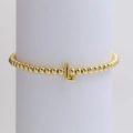 Golden beaded bracelet with letter L pendant displayed on a white cylindrical stand - Gold L