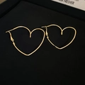 Close-up of minimalist golden heart-shaped metal earrings on black velvet tray - Gold 3D Heart Post