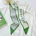 Green and white twilly silk scarf with La liberté script text tied on a white shirt - Geometric Letters